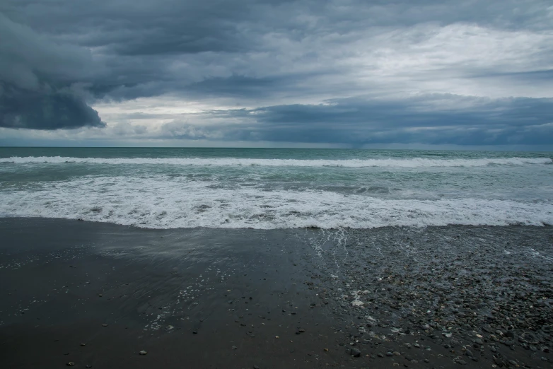 waves roll in to the shore under a cloudy sky