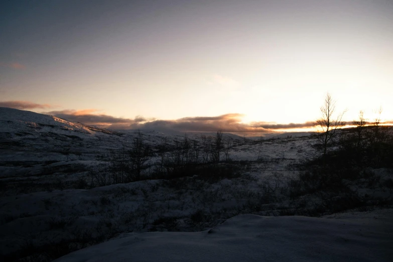 the sun is seen above a landscape in winter