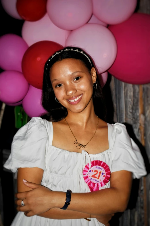 a young woman posing next to some pink and red balloons