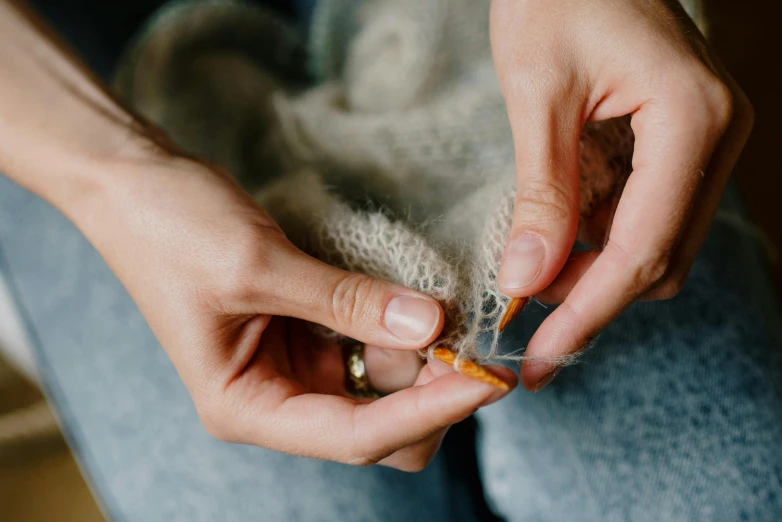 a close up of a person's hands holding a patch of yarn