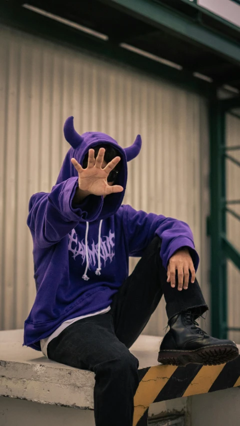 man in purple sweatshirt sitting on a skateboard