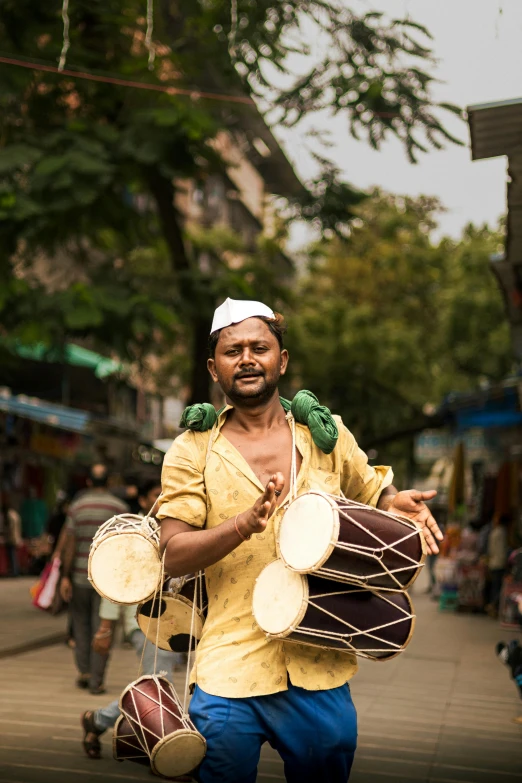 a man carrying two large drum's across the road