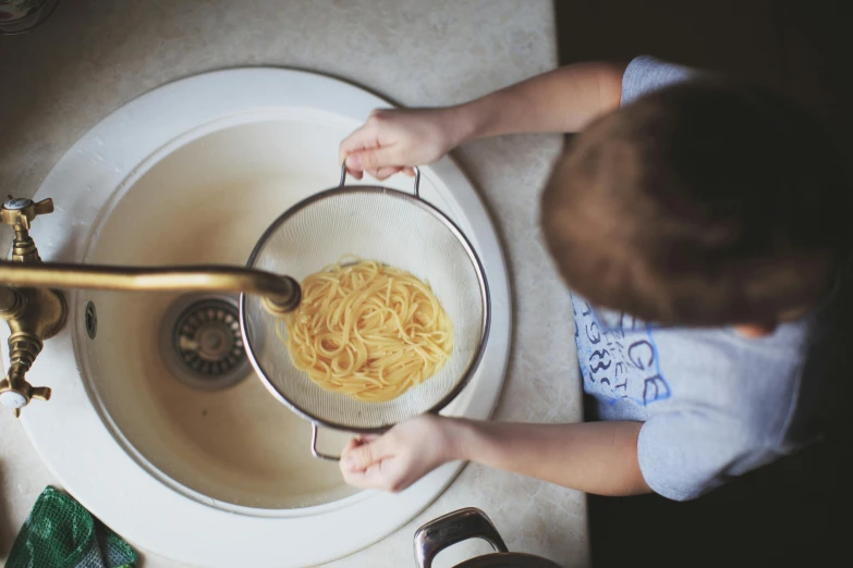 a little boy holding soing in his hands and using it to wash his dish