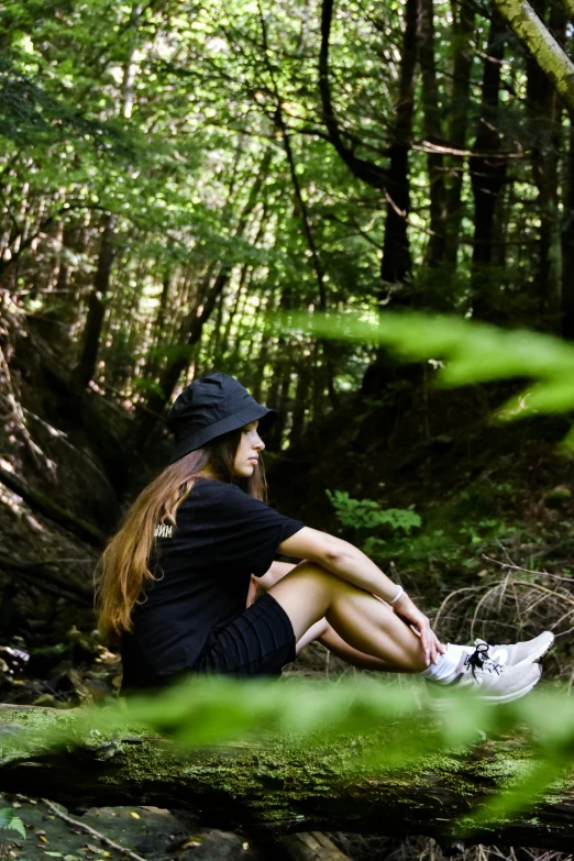 a woman in a black dress is sitting on a log