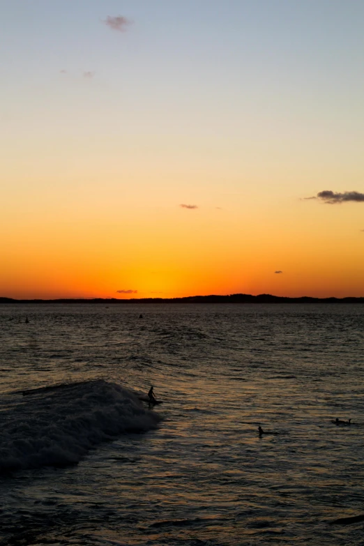 a surfer riding waves at sunset with the sun going down