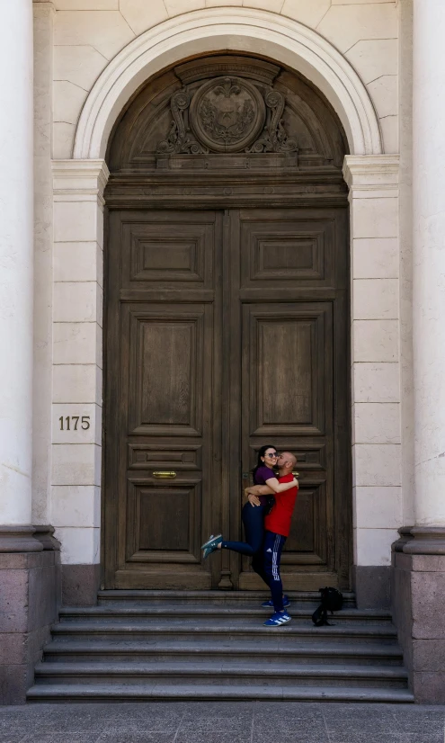 there is a couple kissing in front of a large wooden door