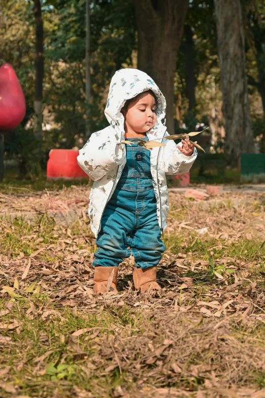 the child wearing a hat is standing in the field