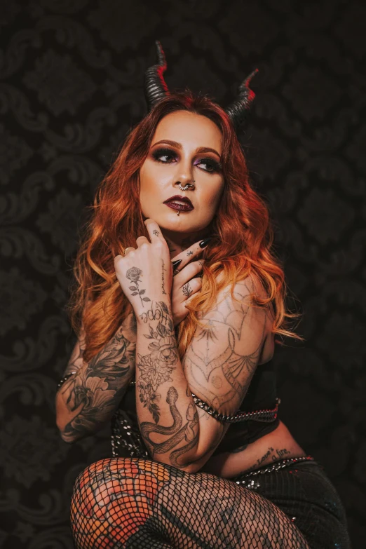 a woman with red hair and horns is sitting down