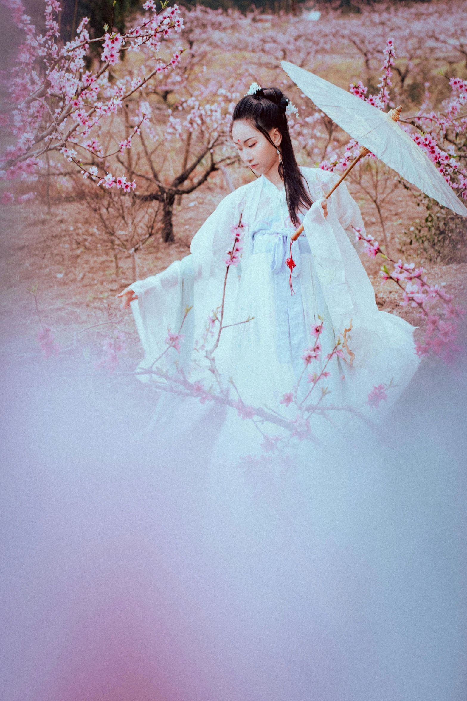 a woman wearing an oriental dress walking through the dirt with a parasol