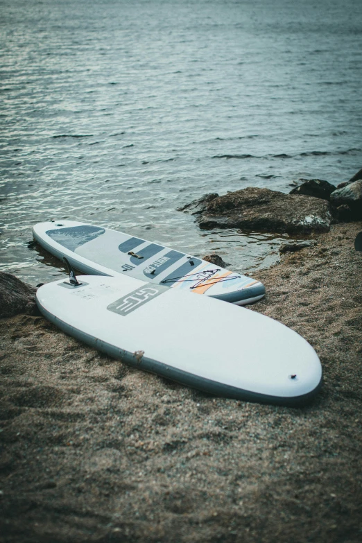 a white surfboard lying on the sand next to the water