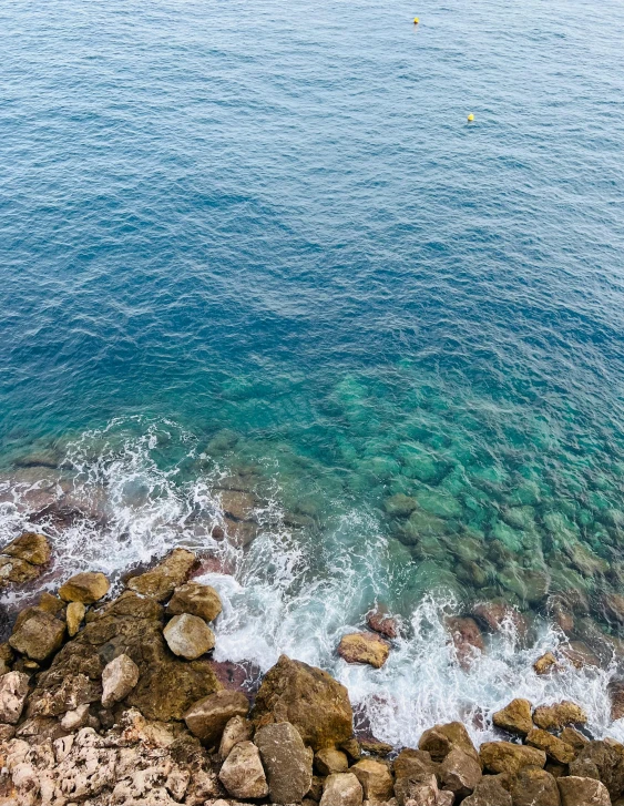 rocks along the shore line in front of a body of water