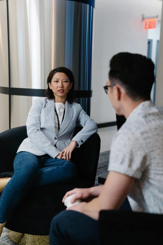 a man sitting on a black chair and another person sitting beside her