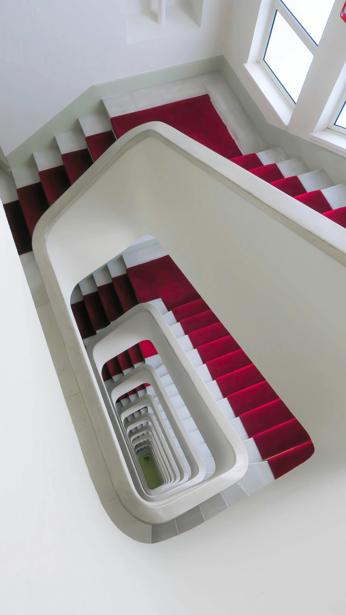 a red and white staircase with white steps and a black window