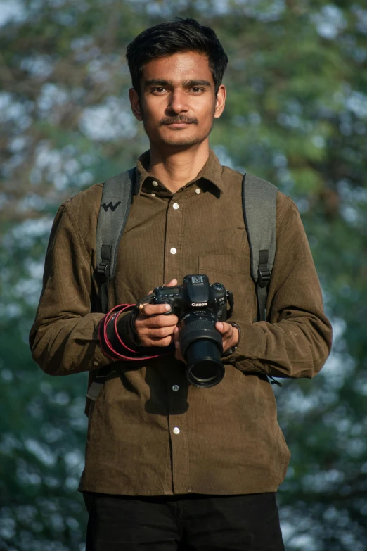 man with a camera taking pictures in front of trees