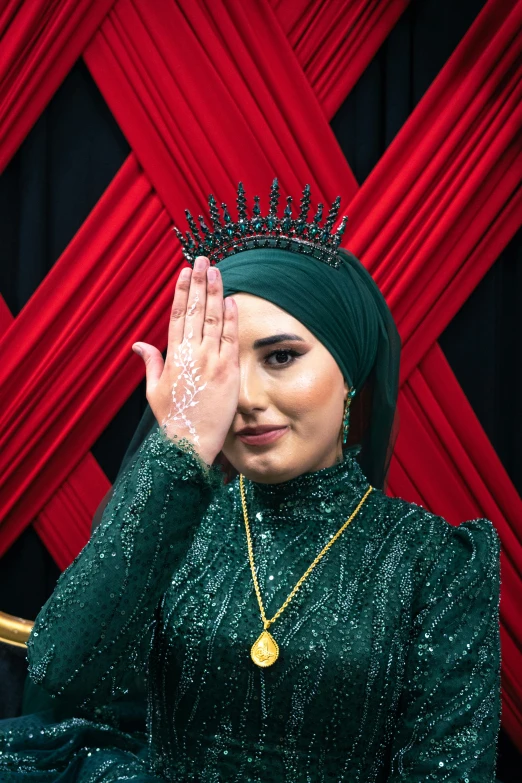 a woman in green is posing and waving her hand