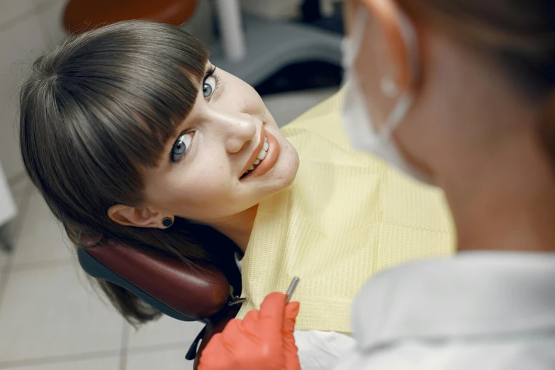 a woman getting her teeth examined while wearing gloves