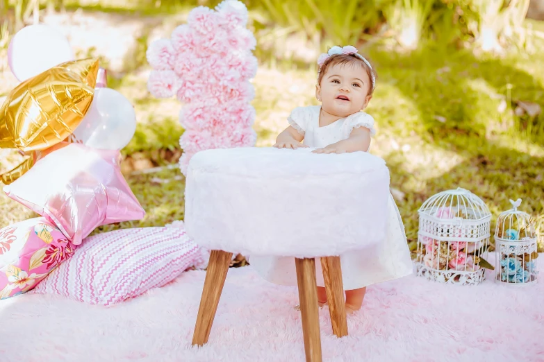 the little girl sits in a high chair next to balloons