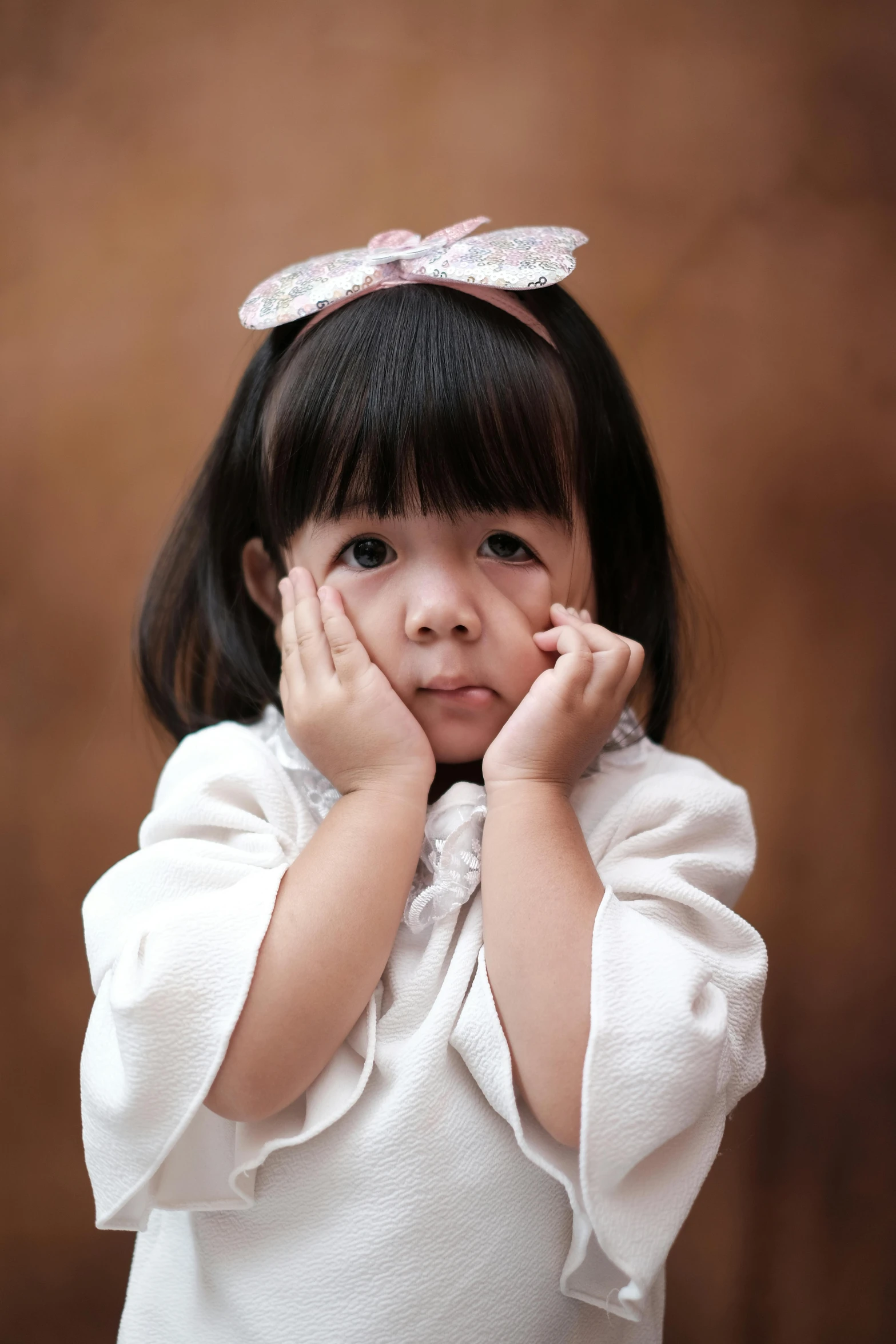 an adorable girl posing for a portrait wearing a white dress