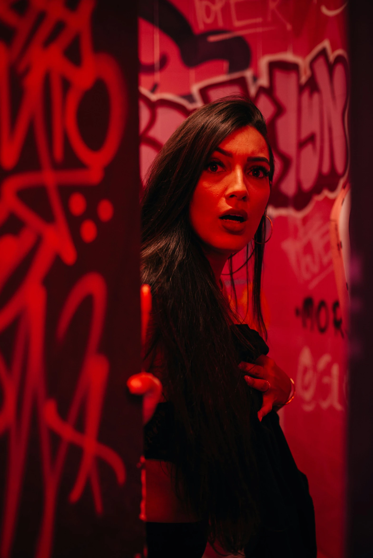 woman with long hair standing in front of red graffiti