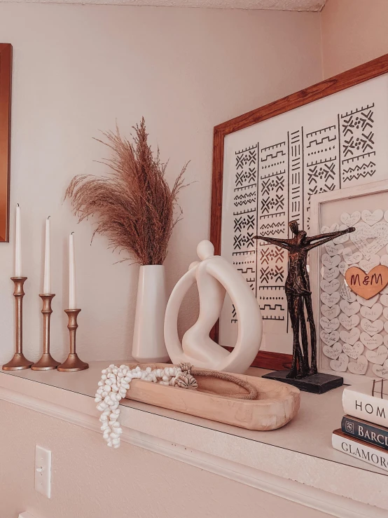 white ceramics and candles on a mantle with art