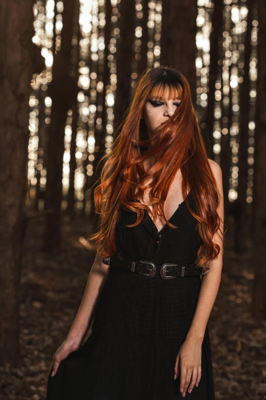 woman with red hair and black dress in the woods