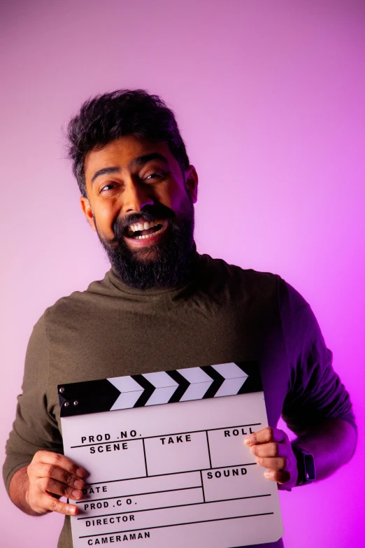 a man is holding up a movie clapper