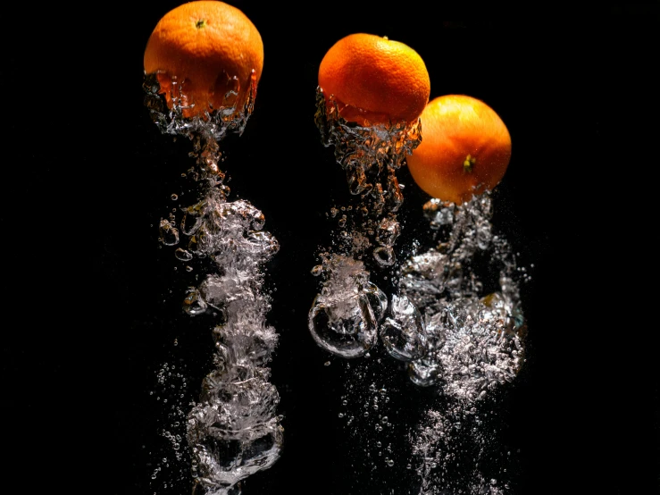three oranges falling into water in the middle of the night