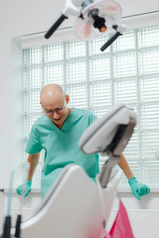 an older man in a dentists uniform and gloves cleaning a dental model with a hand held up to the camera