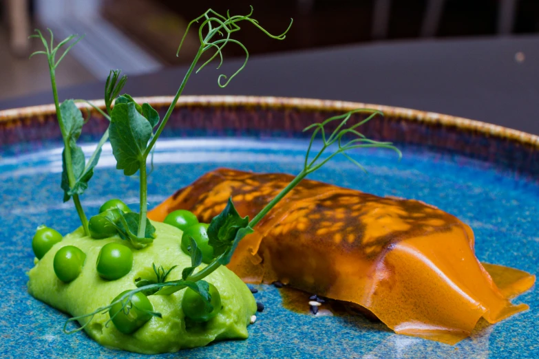 a blue plate with peas and green stuff on it