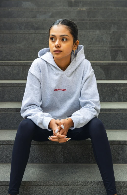 a girl sitting on steps with her hands clasped