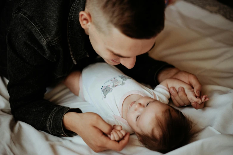 a father holding his baby on top of the bed