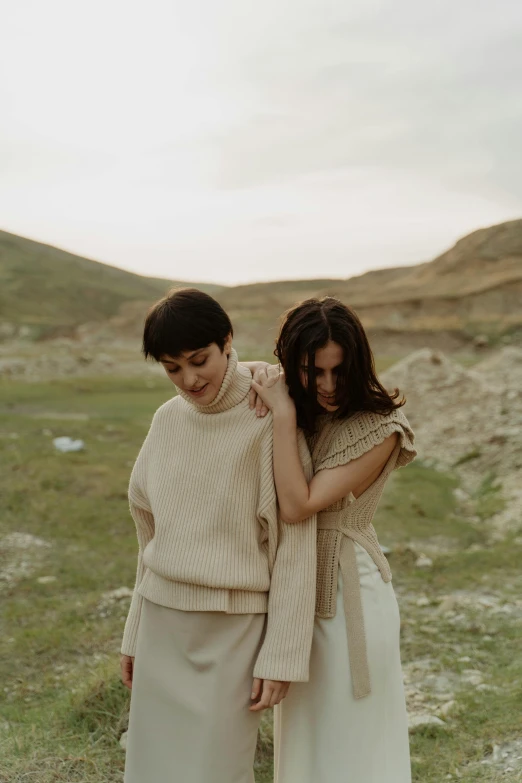 two women are standing together near the grass