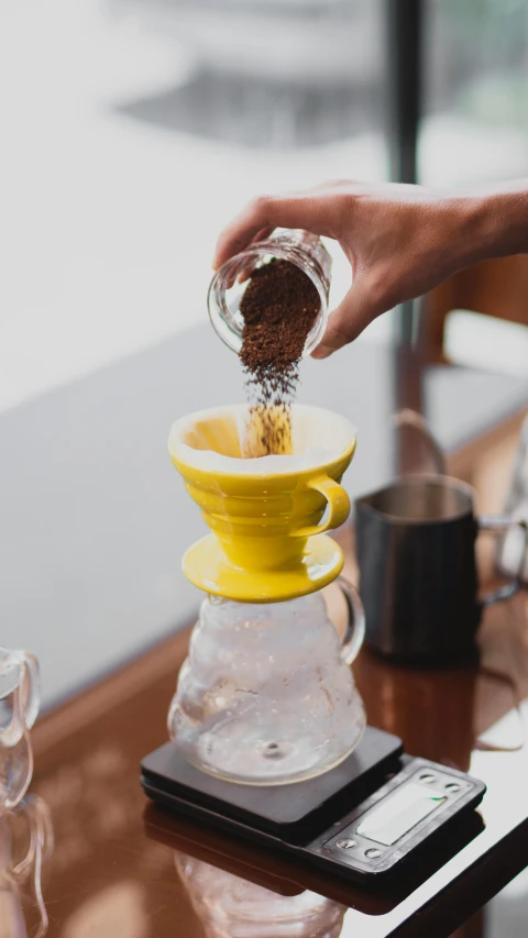 a person pouring coffee into a pour - off pot