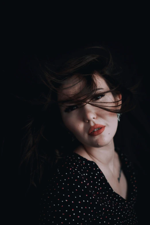 woman in polka dots shirt with hair blowing over her shoulder