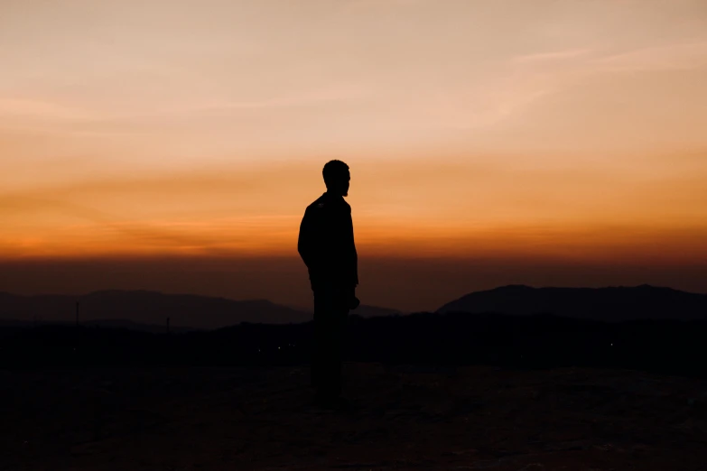 a man standing in the middle of a field as the sun sets