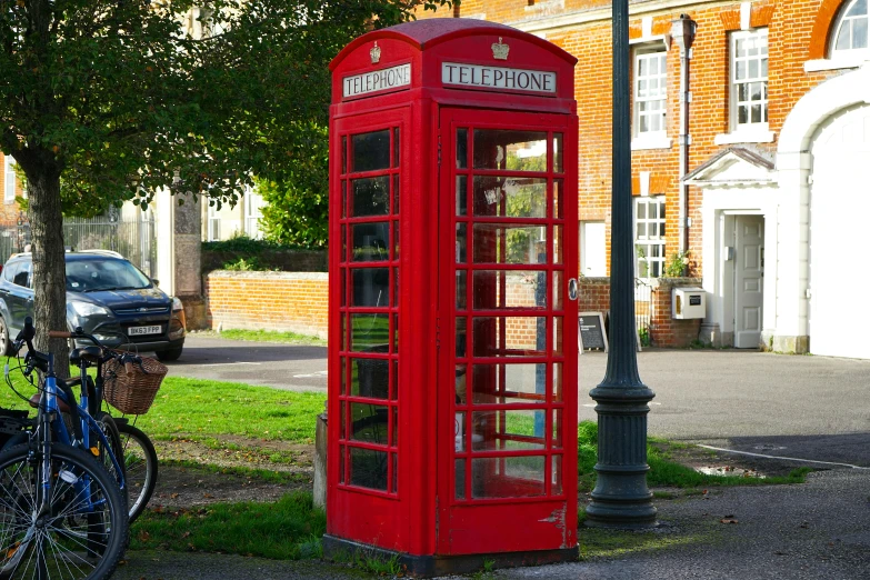 an older red telephone booth next to a bicycle
