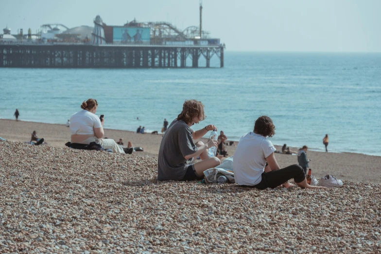 two women sitting on the beach eating sandwiches