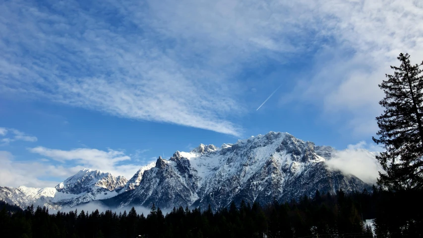 a mountain is shown with snowy mountains and pine trees in the foreground