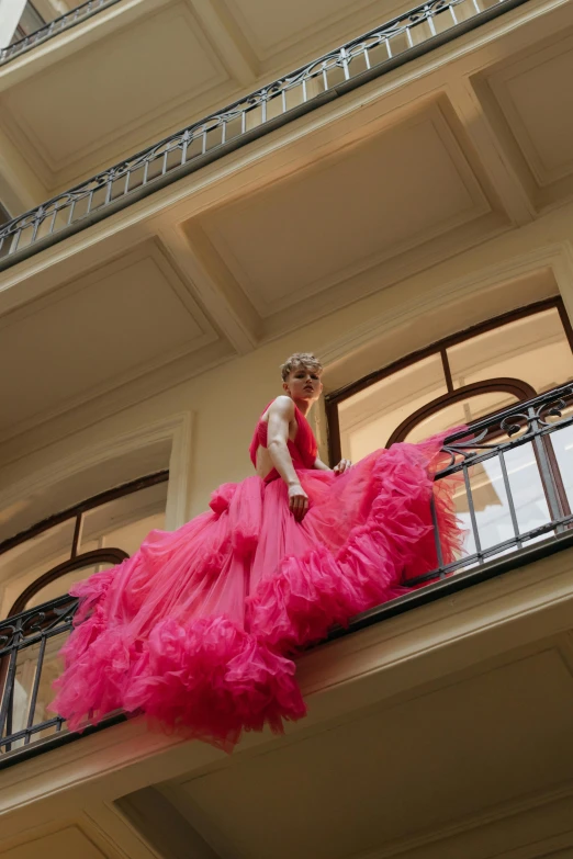 a woman standing on a balcony wearing a long red dress