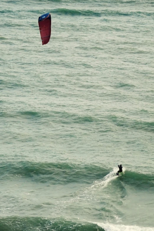 a person on a surfboard under a red para sail