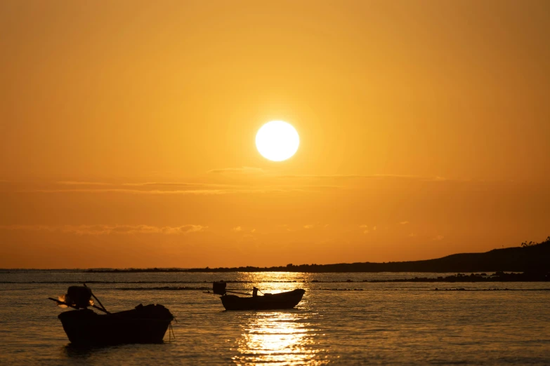 two boats out on the water near a sun set