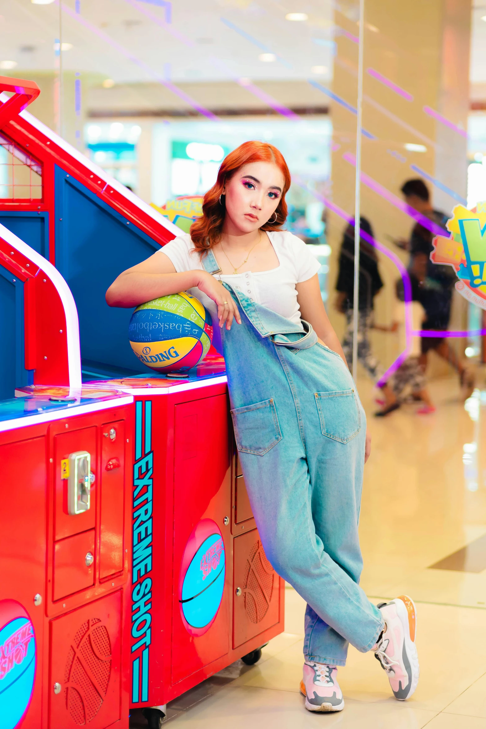 a woman in overalls and pink shoes standing next to an orange machine