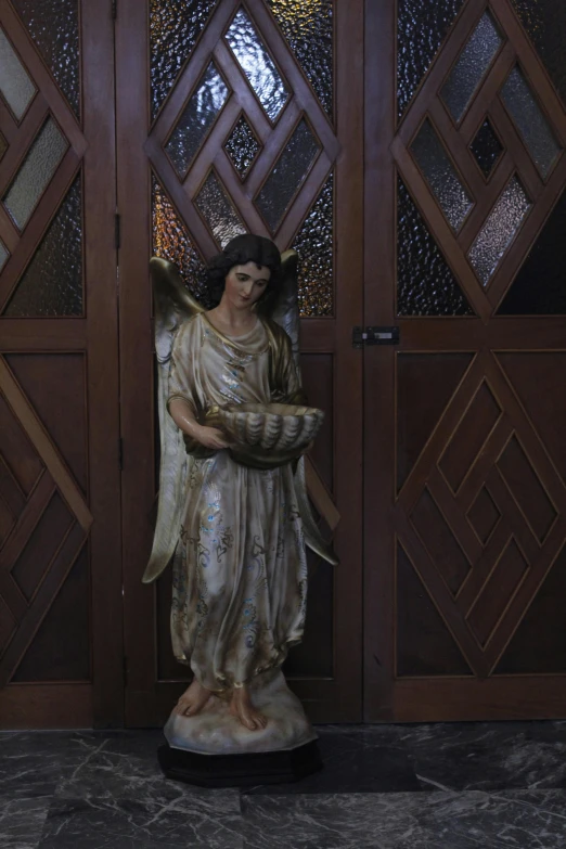 a statue of an angel stands in front of a door