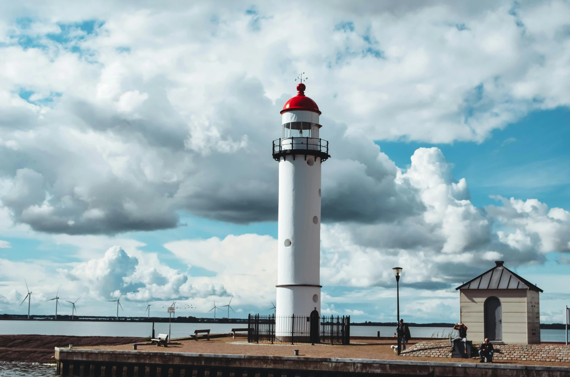 a white lighthouse with a red top near the water