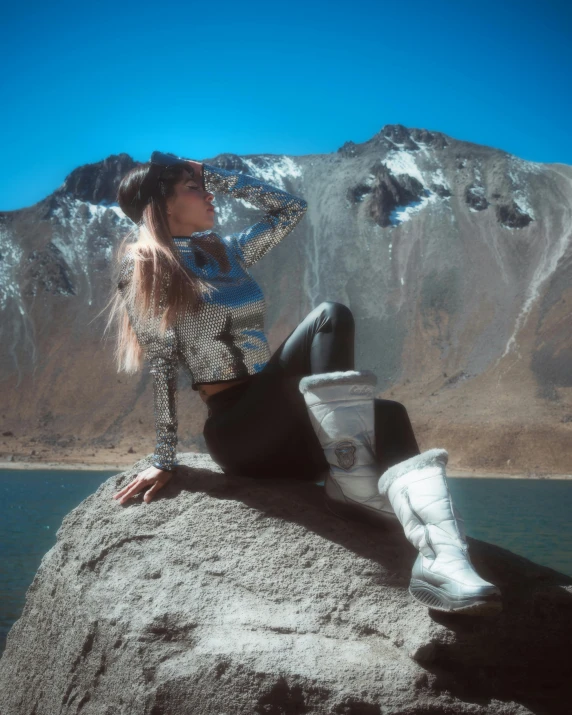 a woman in boots on top of a large rock