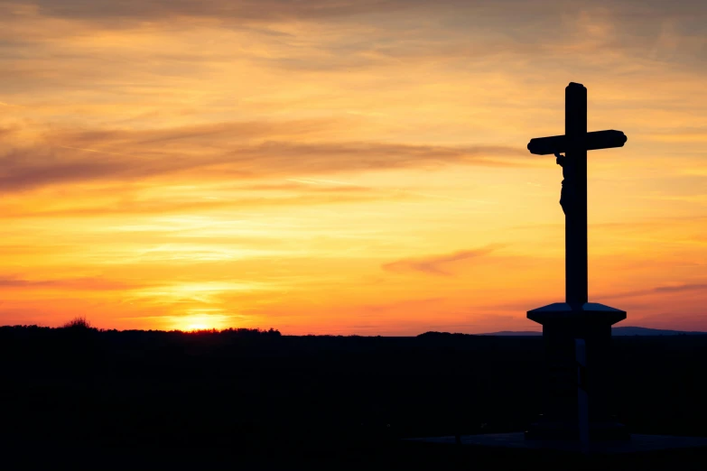 the sun rises over a large cross with the sky in the background