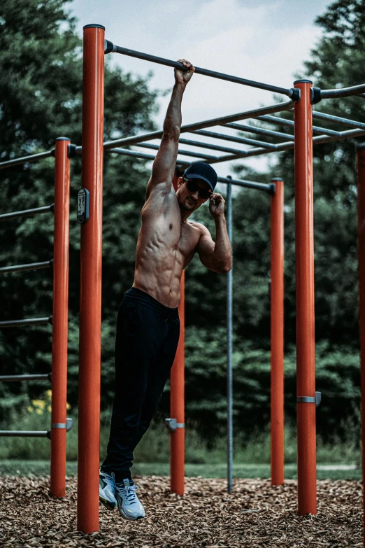 a shirtless man is doing pull ups at a park