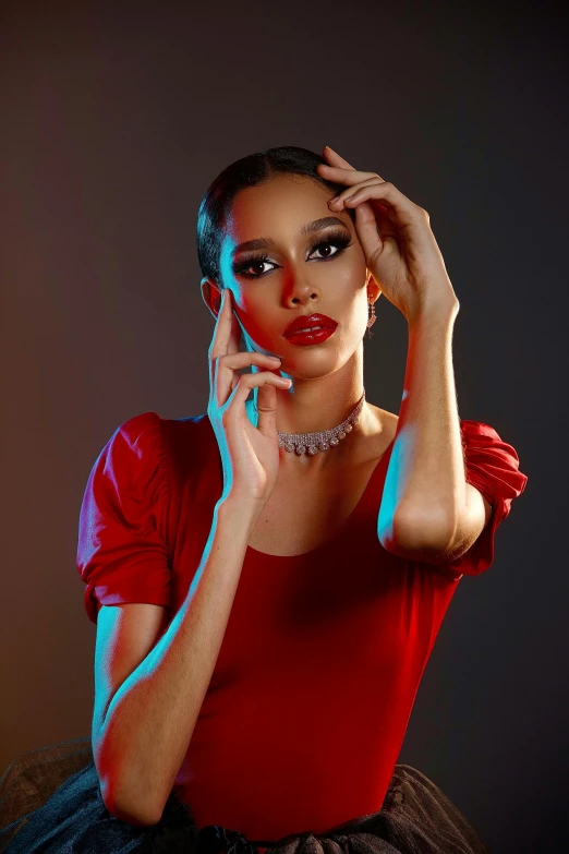 a woman wearing a red top and earrings holding a phone to her ear