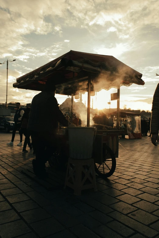 the vendor at the stand has an umbrella