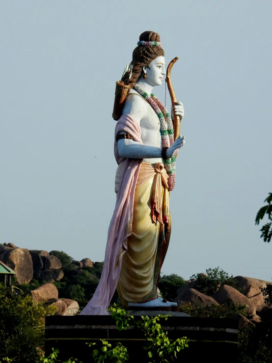 a statue of a woman with a flute in front of a field of rocks